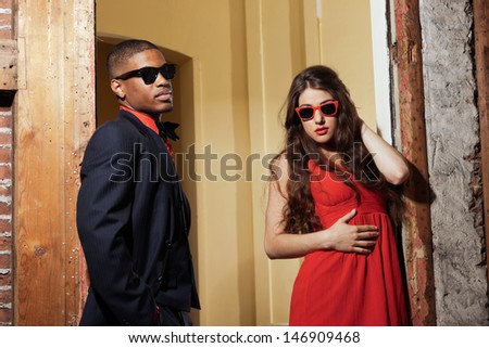 Retro fashion mixed race wedding couple wearing black suit and red dress and sunglasses.
