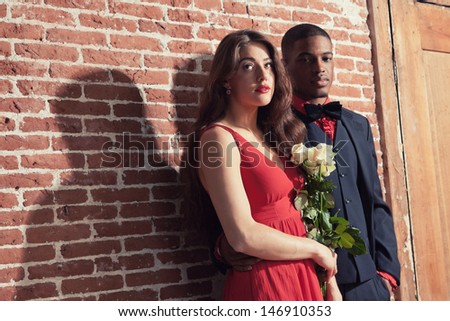 Urban cool vintage fashion mixed race wedding couple wearing black suit and red dress.