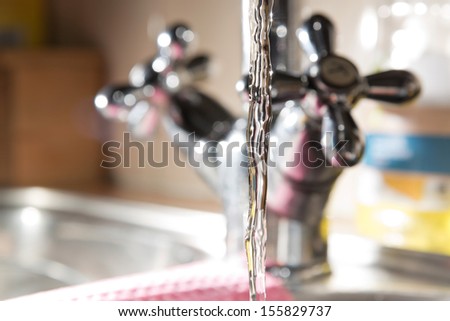 Close-up of water stream out of classic kitchen tap.