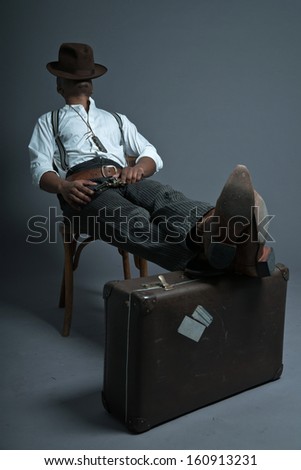 Sleeping retro afro america western cowboy man with mustache. Sitting in wooden chair. Resting his legs on suitcase. Wearing brown hat. Cool tough guy.