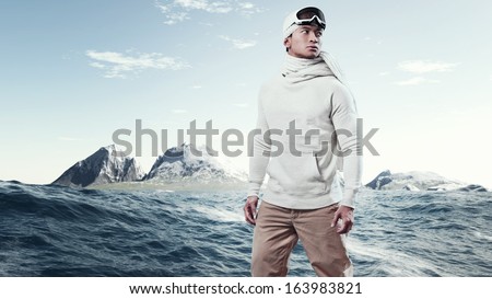 Asian winter holiday fashion man in arctic snow landscape. Wearing woolen hat, sweater, scarf and ski glasses.