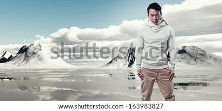 Asian winter fashion man in snow mountain landscape. Wearing white sweater and scarf and brown trousers.