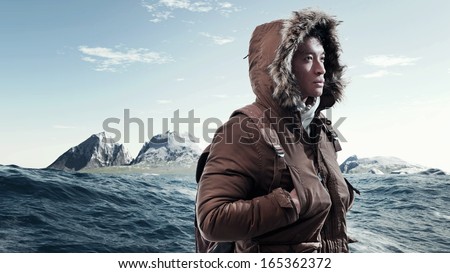 Asian Winter Sport Fashion Man With Backpack In Arctic Mountain Landscape. Wearing Brown Jacket With Fur Hoody And White Gloves.