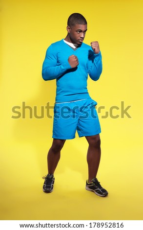 Athletic black man in sportswear fashion. Boxer. Intense colors. Studio shot against yellow.