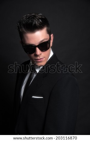 Retro fifties fashion man wearing black sunglasses with suit and tie. Studio shot.