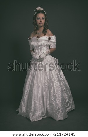 Victorian fashion woman wearing white dress. Studio shot against grey.