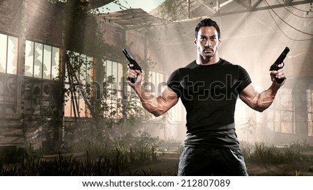 Action hero muscled man holding two guns. Standing in abandoned building. Wearing black t-shirt and pants.