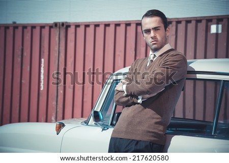 Retro fifties business fashion man leaning against vintage car.