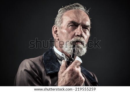 Pipe smoking vintage characteristic senior man with gray hair and beard. Studio shot against dark background.