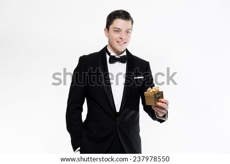 New year\'s eve fashion man wearing black dinner jacket. Holding golden present. Isolated against white.