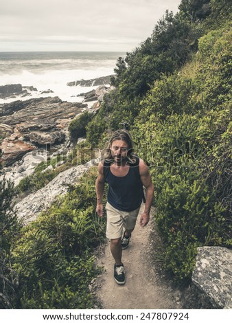 Male hiker with long blonde hair walking on path at Tsitsikamma National Park. Eastern Cape. South Africa.