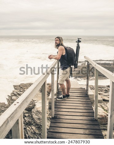 Man with long blonde hair standing on wooden bridge at Tsitsikamma National Park. Eastern Cape. South Africa.