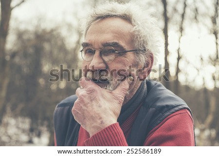 Close up Serious Old Man in Glasses Looking Afar at the Woodland with Hand on the Face