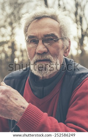 Close up Serious Elderly Man Wearing Jacket and Eyeglasses at the Forest Looking Afar, Emphasizing Thinking of Something.