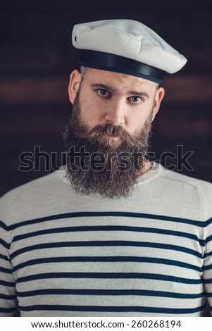 Close Up Portrait of a Gorgeous Man with Long Goatee Wearing Black and White Stripe Shirt and Sailor Hat, Looking at the Camera.