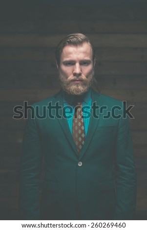 Portrait of a Middle Age Man with Goatee Beard, Wearing Formal Wear, Looking at the Camera on a Wooden Wall Background.