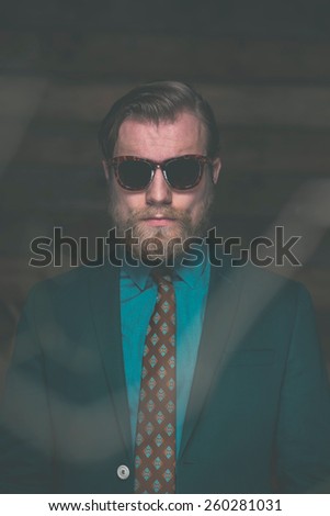 Close up Portrait of an Adult Man with Goatee Beard Wearing Formal Fashion with Sunglasses Facing at the Camera.