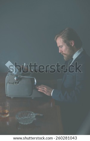 Handsome young businessman or business clerk sitting working at his desk typing on an old vintage typewriter with aged faded effect
