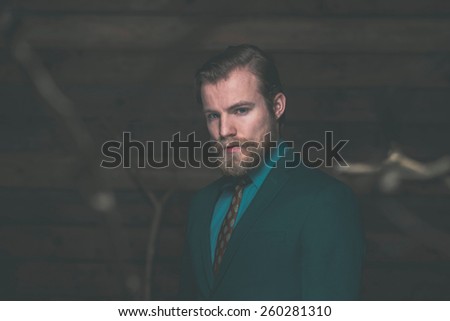 Close up Gorgeous Middle Age Man with Goatee Beard Wearing Green Formal Fashion on a Rustic Wooden Wall Background
