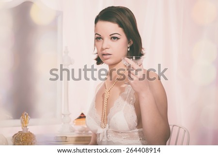 Close up Young Woman, Wearing White Night Wear, Holding a Glass of Wine While Looking to the Right of the Frame