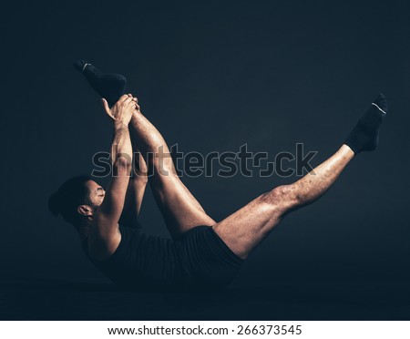 Healthy Man Doing Reclining Big Toe Yoga Pose or Supta Parsvasahita on the Floor with Black Background.