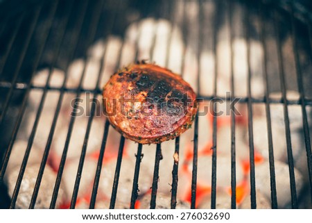 Seared succulent thick beef steak cooking over a hot fire during an outdoor summer barbecue, close up view