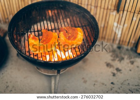 Fresh healthy pumpkin grilling over hot coals on a BBQ for a delicious vegetable accompaniment to a summer meal