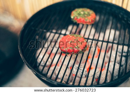 Thick beef steak medallions grilling on a fire in a portable outdoor barbecue in the backyard in a healthy outdoor lifestyle concept