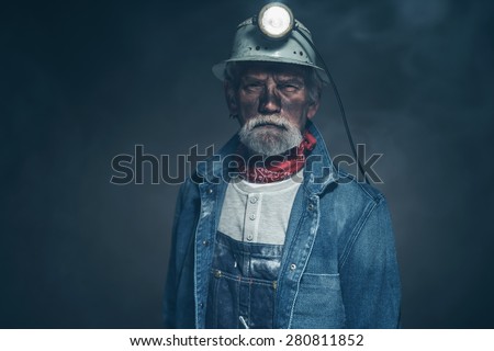 Close up Adult Male Gold Miner with Dirt and Facial Hair on his Face, Staring at the Camera on a Fuzzy Black Background.