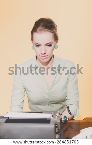 Retro 1950 blonde secretary woman sitting behind desk working on typewriter.