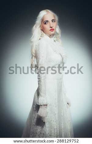 Portrait of Mystical Looking Woman with White Hair Dressed All in White, Woman Wearing Victorian Style Lace Gown and Gloves Standing and Looking Over Shoulder