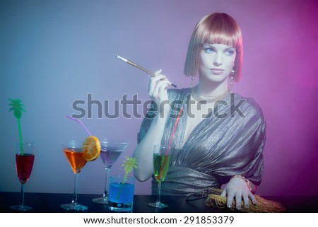 Glamorous Sophisticated Woman with Red Hair Wearing Shiny Retro Gown Smoking Cigarette at Bar Covered in Cocktails in Smoky Disco Night Club