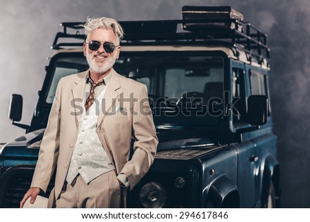 Fashionable Matured Guy in Formal Wear with Sunglasses, Leaning his Back Against his Vintage Vehicle with One Hand in the Pocket.