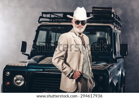 Good Looking Senior Man Wearing Formal Fashion with White Cowboy Hat and Sunglasses, Posing Against his Vintage 4x4 Vehicle.