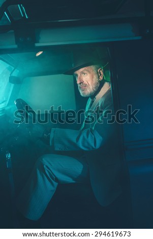 Pensive Senior Elegant Man Seating on Driver\'s Seat of a Four-Wheel Vehicle with Door Open on One Fuzzy Dark Night.