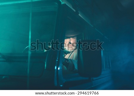 Bearded Senior Guy Looking at the Side Mirror to See the Rear View While Driving his Vehicle in the Middle of the Night.