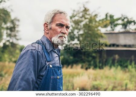 Close up Thoughtful Senior Bearded Man Looking Into the Distance at the Farm While Looking Into the Distance.