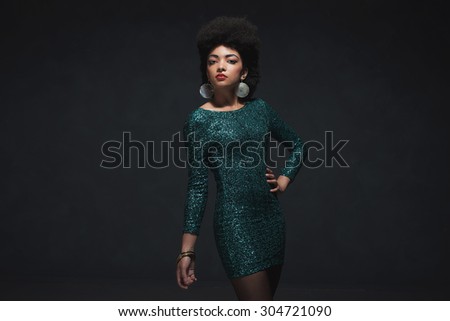 Three Quarter Shot of an African-American Woman Posing in an Elegant Sparkling Green Dress, Looking at the Camera. Isolated on Black Background