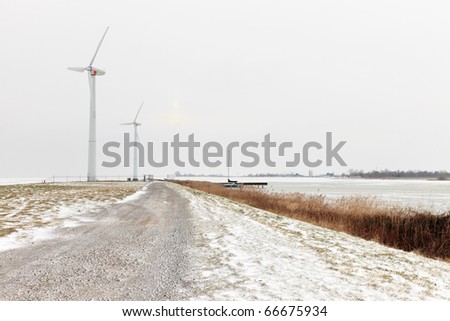 Winter landscape with dike and frozen sea and windmills in the background, Marken, the Netherlands