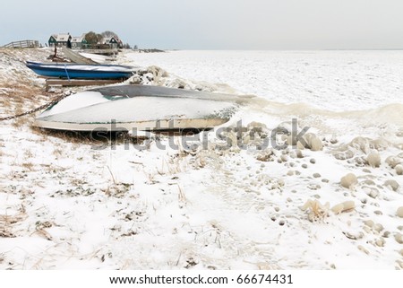 Winter landscape with frozen sea and boat on shore, Marken, the Netherlands