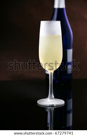 Ice cold frosted glass of champagne with blue bottle on black ... Ice cold frosted glass of champagne with blue bottle on black ...