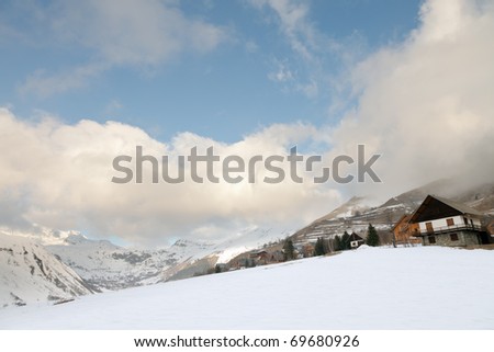 Alpine winter scenery with chalets under blue cloudy sky
