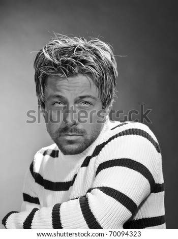 Portrait of a casual serious young man. Short blond hair. Black and white. Studio portrait.