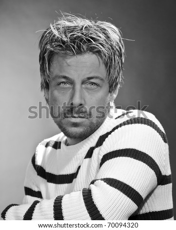 Portrait of a casual serious young man. Short blond hair. Black and white. Studio portrait.