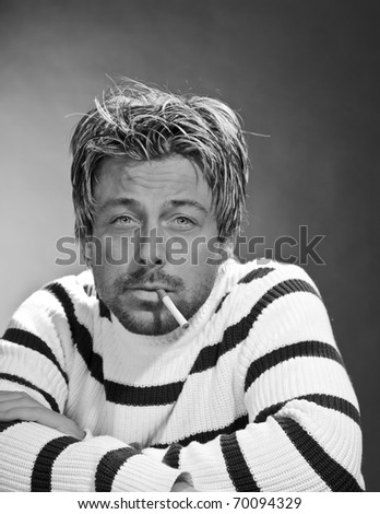 Portrait of a casual young man with cigarette. Short blond hair. Black and white. Studio portrait.