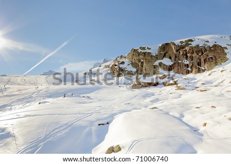 Winter mountain landscape with big rock under blue sky with sun rays. Alps. France.