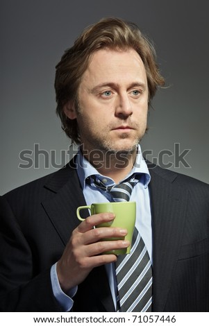 Studio portrait of serious young business man holding a cup of coffee. In thought. In mind. Thinking. Concentration. Having a break.
