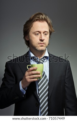 Studio portrait of serious young business man holding a cup of coffee. In thought. In mind. Thinking. Concentration. Having a break.