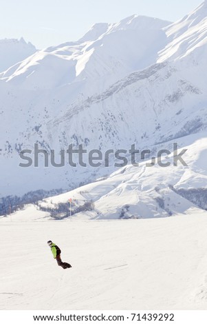 Snowboarder down hill in winter snow mountain landscape. France. Alps.