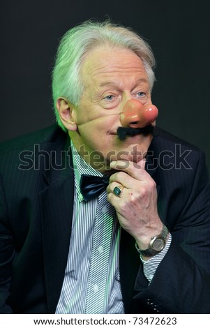 Senior man with party nose and moustache in suit. Funny. Weird. Serious.Studio portrait.